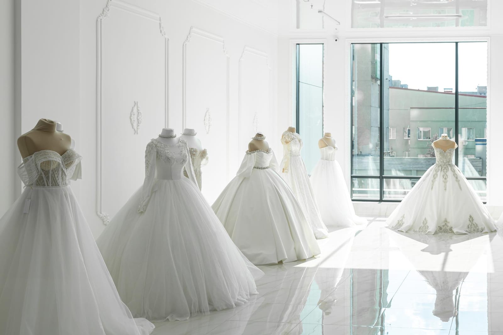 Vestidos de noiva expostos em manequins dentro de vitrine de showroom